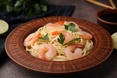 Photo of Tasty spaghetti with shrimps and parsley on brown table, closeup