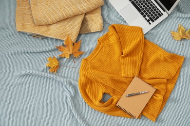 Flat lay composition with cozy knitted sweater on blanket. Space for text