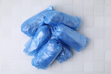 Rolled blue shoe covers on white tiled table, top view