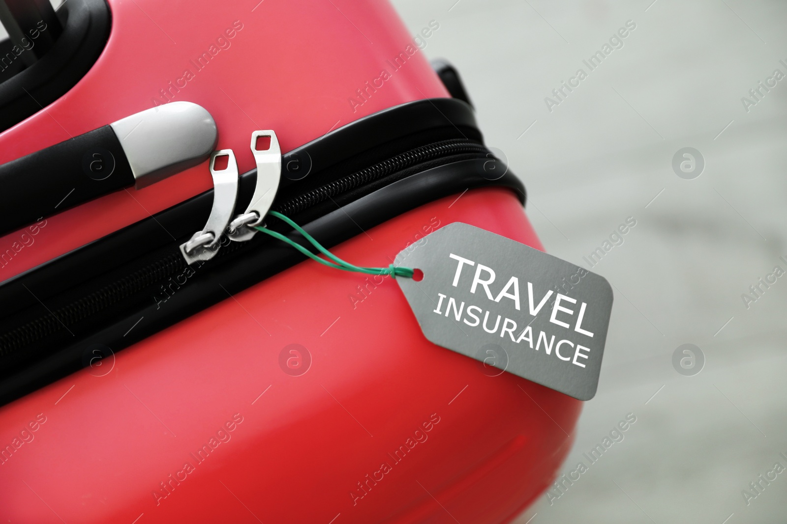 Photo of Stylish suitcase with travel insurance label on blurred background, closeup. Space for text