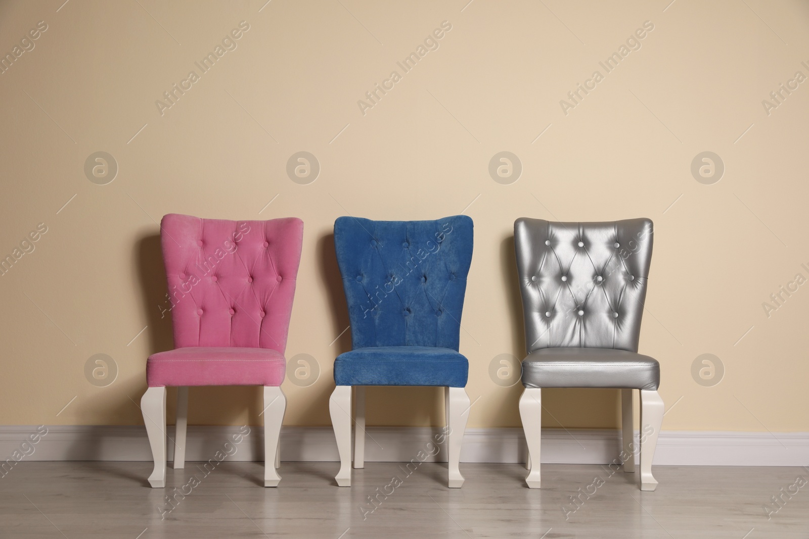 Photo of Different elegant stylish chairs near beige wall