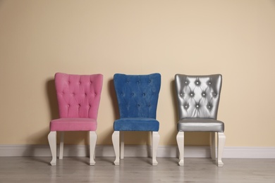 Photo of Different elegant stylish chairs near beige wall