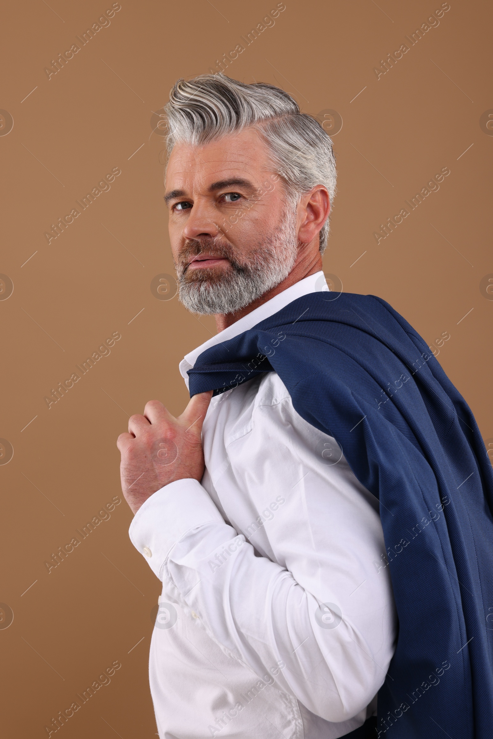 Photo of Portrait of confident man with beautiful hairstyle on light brown background