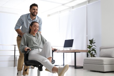 Photo of Young colleagues having fun with chair in office