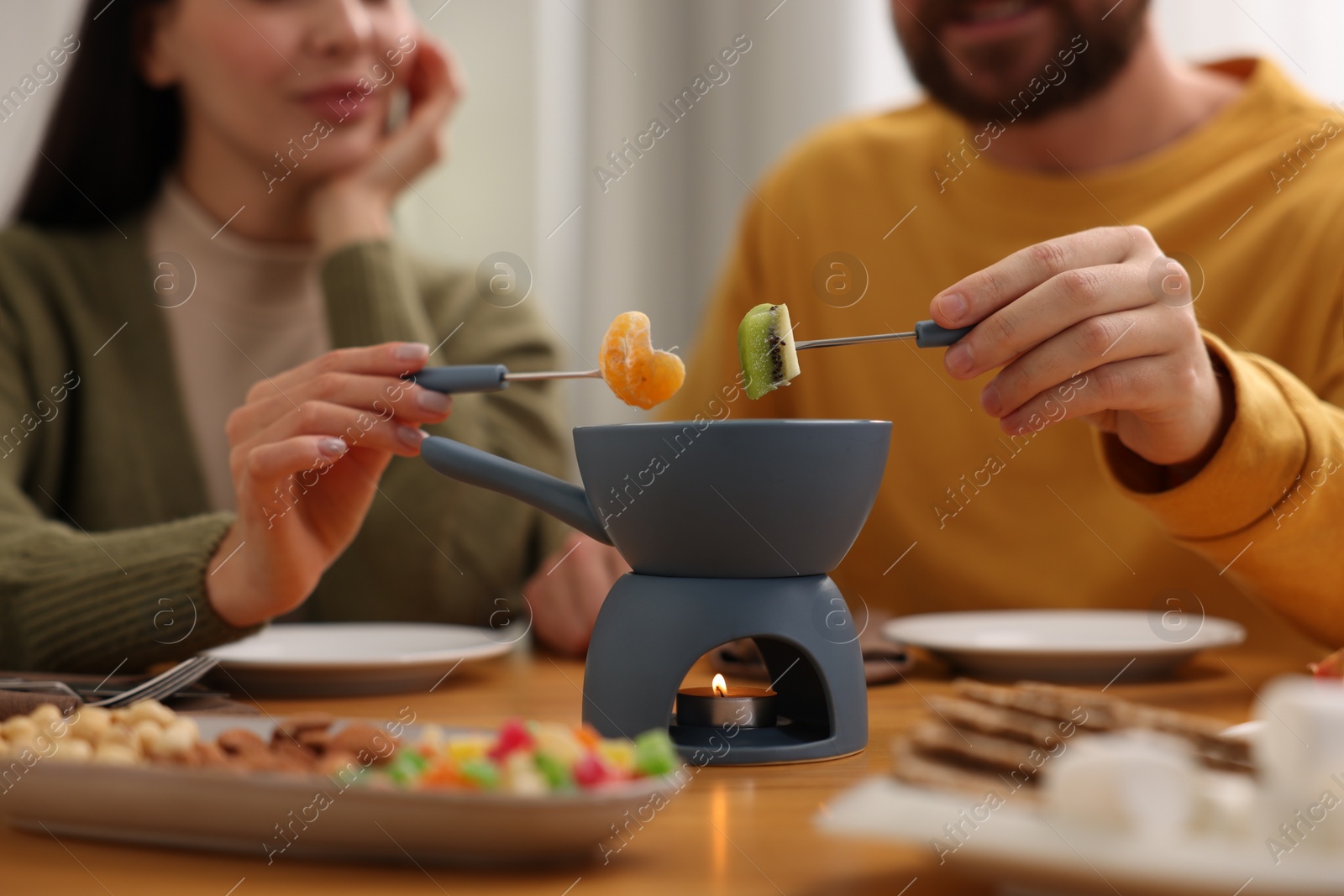 Photo of Couple enjoying fondue during romantic date indoors, closeup