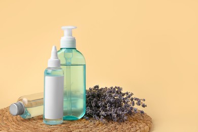 Photo of Bottles with cosmetic products and dried lavender flowers on beige background. Space for text