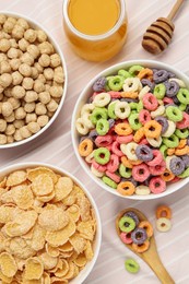Photo of Different breakfast cereals and honey on napkin, flat lay