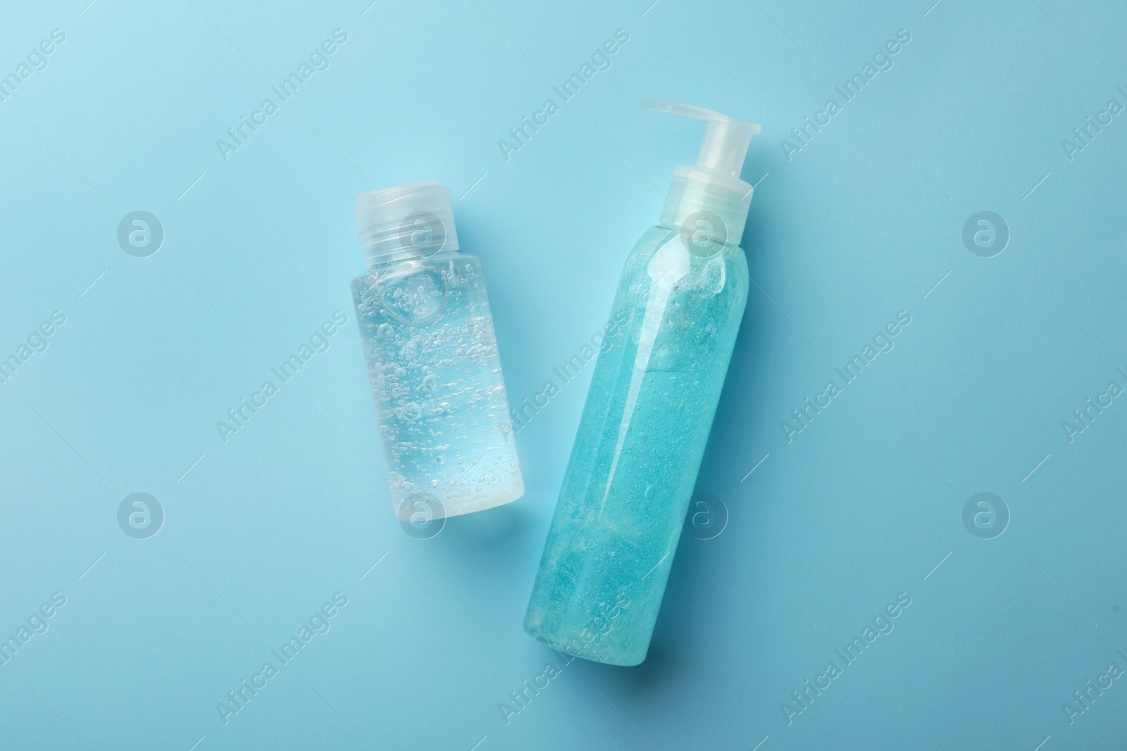 Photo of Bottles with different cosmetic gels on light blue background, flat lay