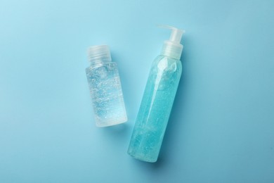 Photo of Bottles with different cosmetic gels on light blue background, flat lay