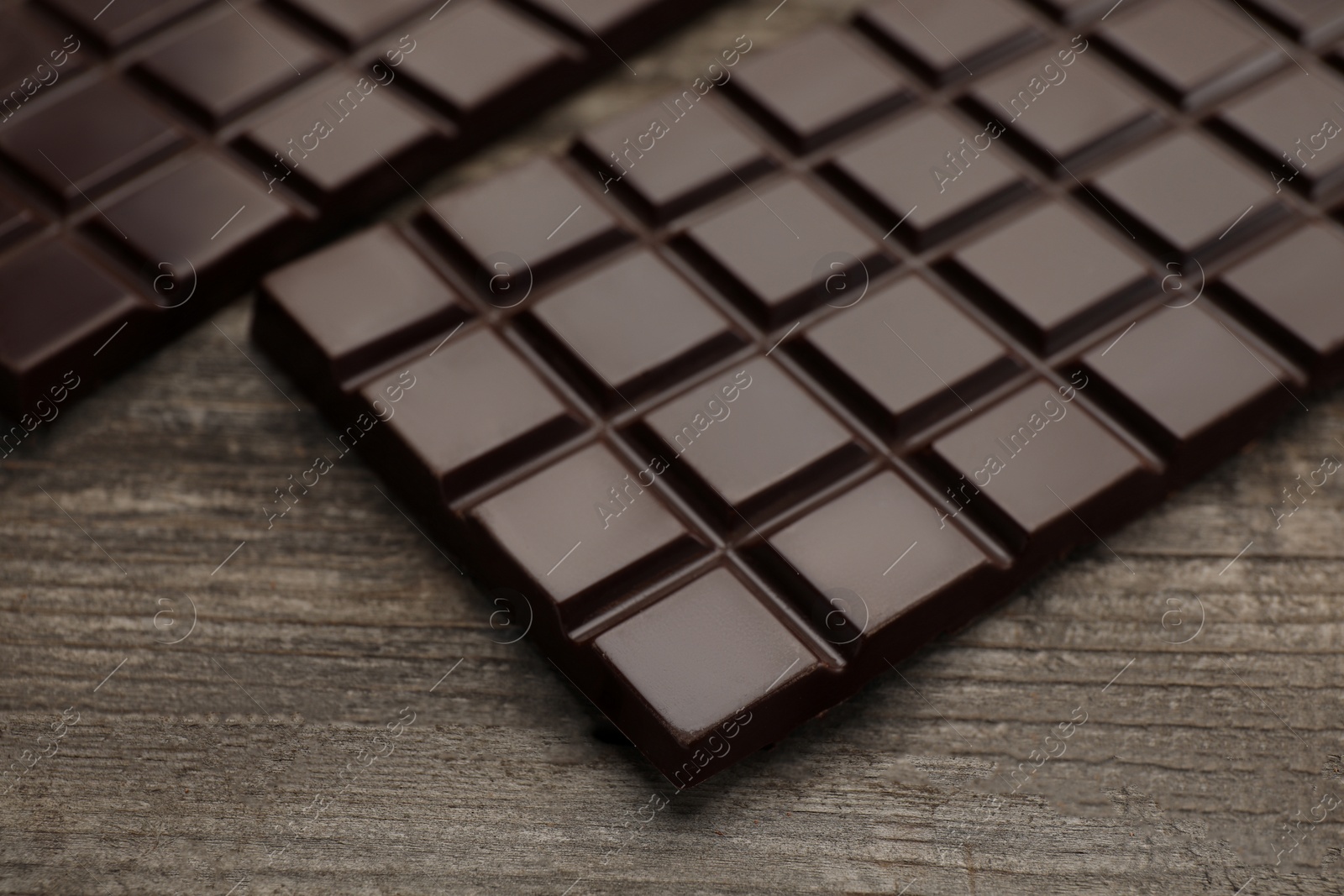 Photo of Delicious dark chocolate bars on wooden table, closeup