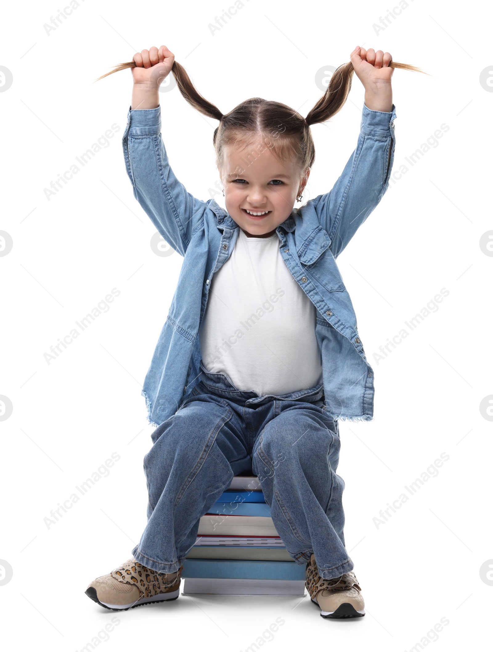 Photo of Cute little girl sitting on stack of books against white background