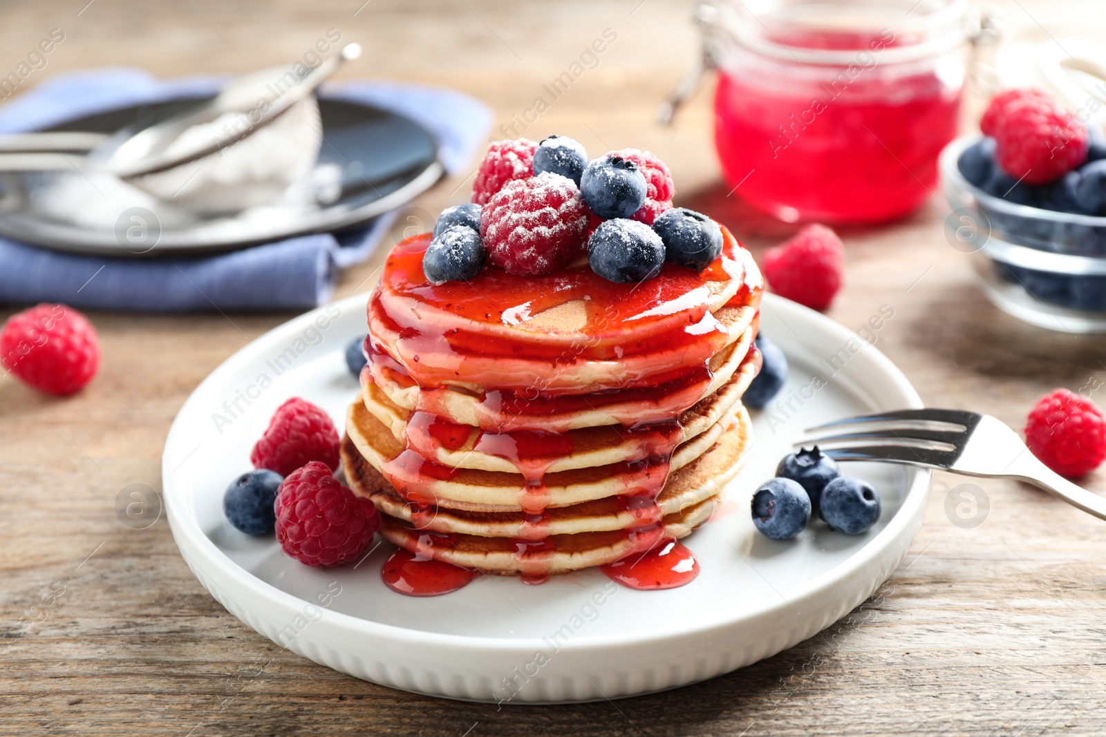 Photo of Delicious pancakes with fresh berries and syrup on wooden table