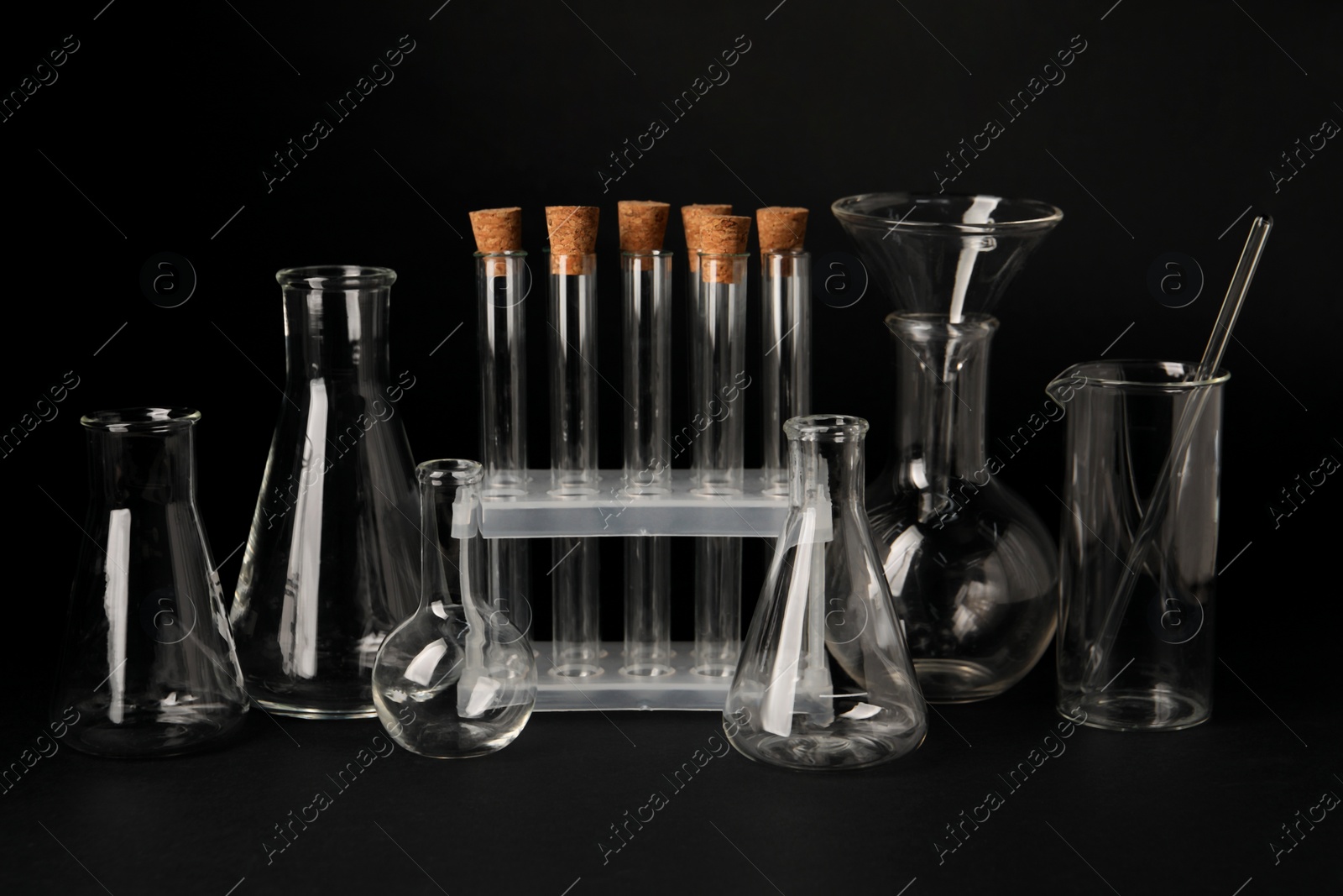 Photo of Different laboratory flasks and test tubes on black background