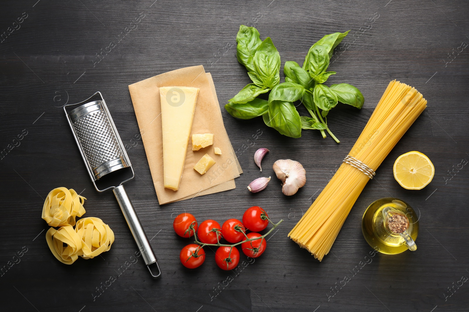 Photo of Different types of pasta, products and garter on dark wooden table, flat lay