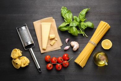 Photo of Different types of pasta, products and garter on dark wooden table, flat lay