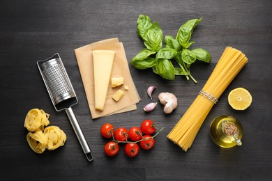 Different types of pasta, products and garter on dark wooden table, flat lay