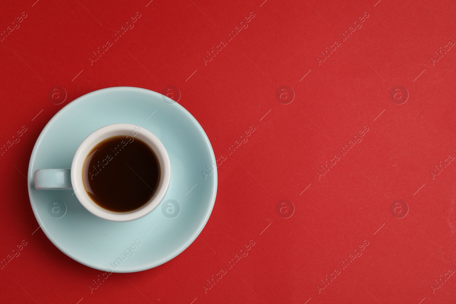 Photo of Tasty coffee in cup on red background, top view. Space for text