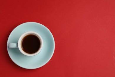 Tasty coffee in cup on red background, top view. Space for text