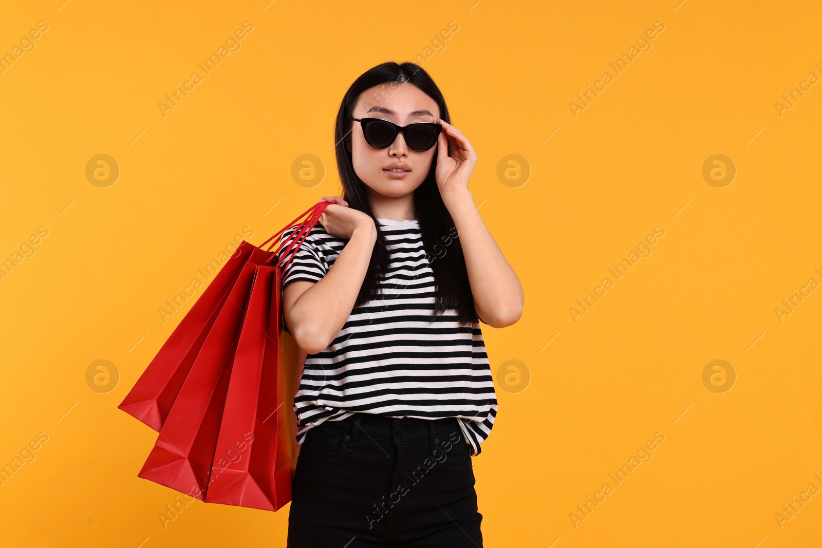 Photo of Beautiful woman with shopping bags on yellow background