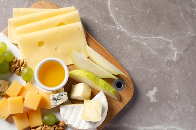 Board with different kinds of delicious cheese and snacks on marble background, top view. Space for text