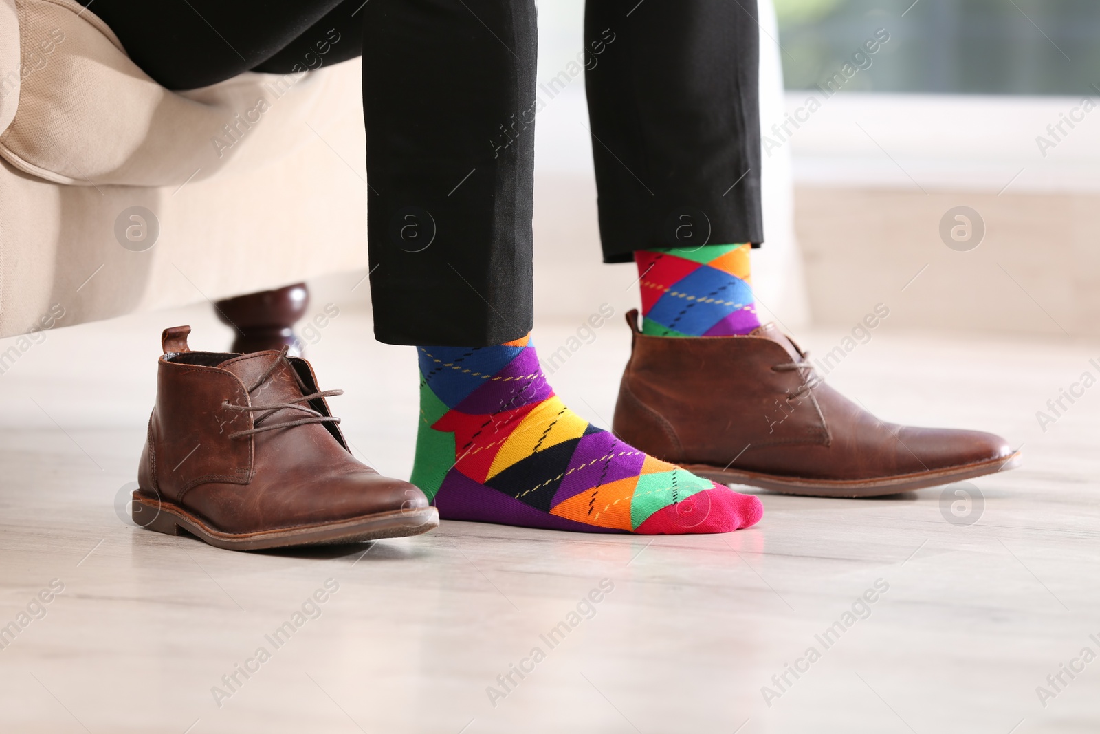 Photo of Man in stylish socks and one shoe on couch indoors, closeup