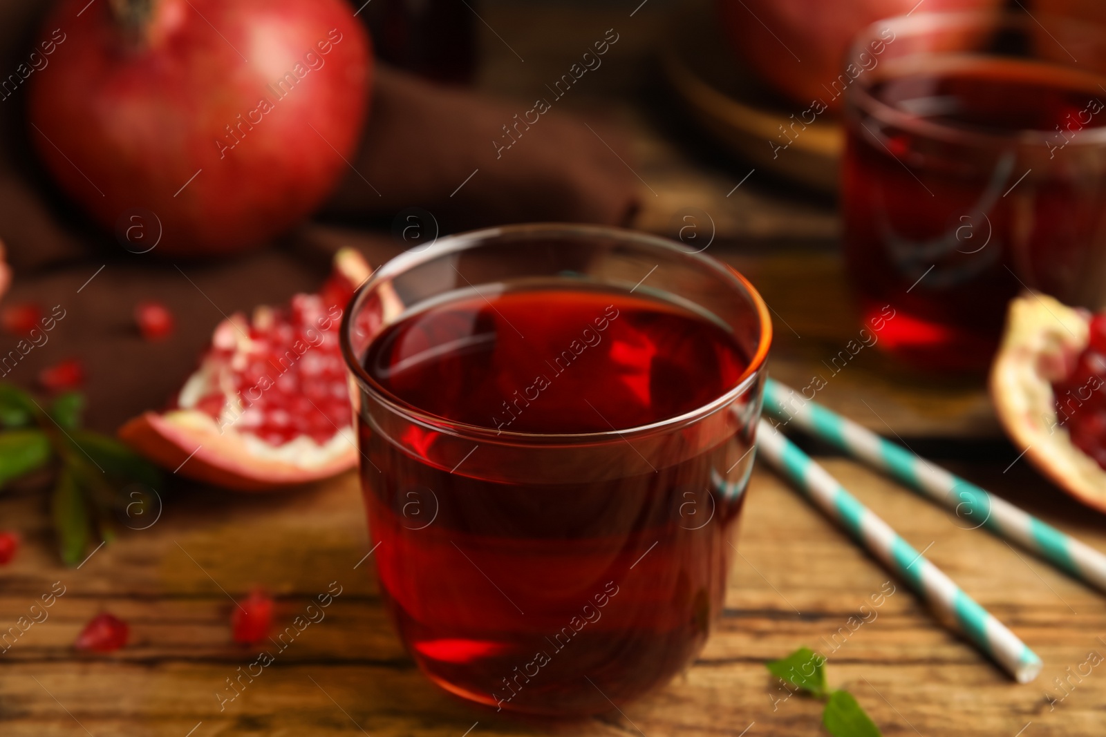Photo of Delicious pomegranate juice and fresh fruits on wooden table
