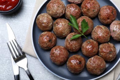 Photo of Tasty cooked meatballs with parsley served on light grey table, flat lay