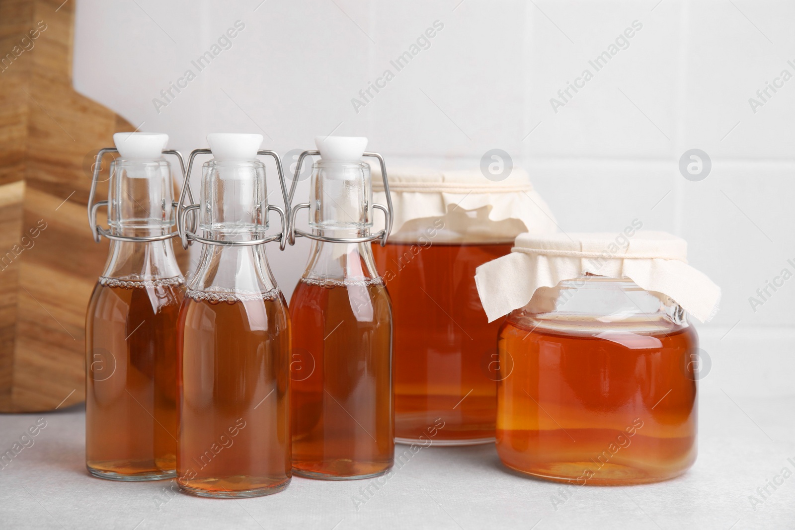 Photo of Tasty kombucha in glass jars and bottles on white table