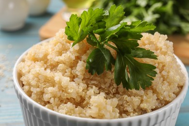 Photo of Tasty quinoa porridge with parsley in bowl on table, closeup