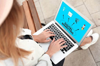 Image of Digital marketing concept. Woman working with laptop on bench, above view