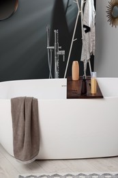 Photo of Stylish bathroom interior with ceramic tub and cosmetic products