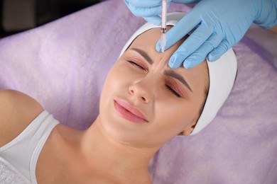 Photo of Young woman getting facial injection in beauty salon. Cosmetic procedure