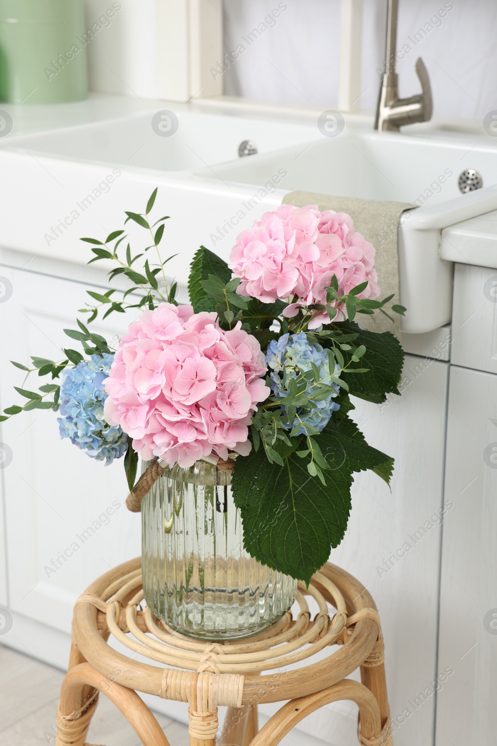 Photo of Beautiful hortensia flowers in vase on stand indoors