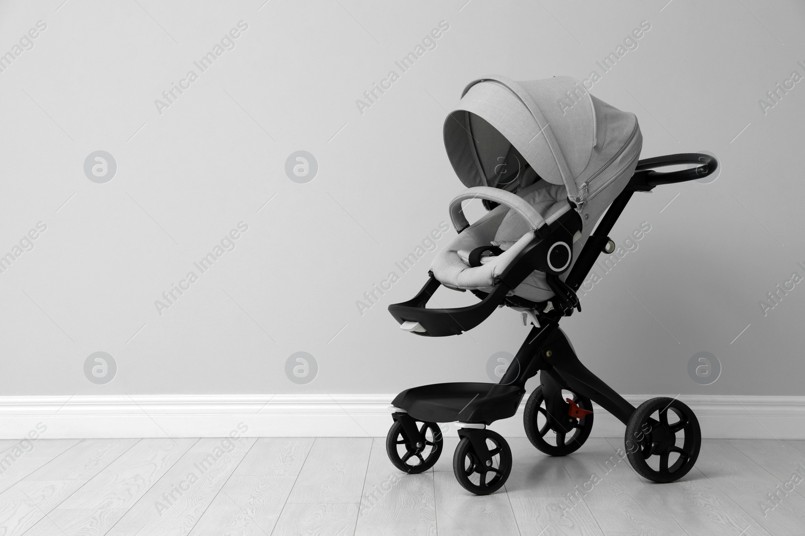 Photo of Baby carriage. Modern pram near light grey wall, space for text