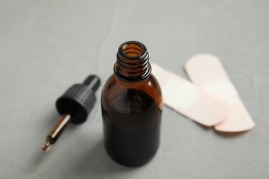 Photo of Bottle of medical iodine, dropper and sticking plasters on grey table, closeup