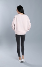 Photo of Young woman in sweater on grey background. Mock up for design