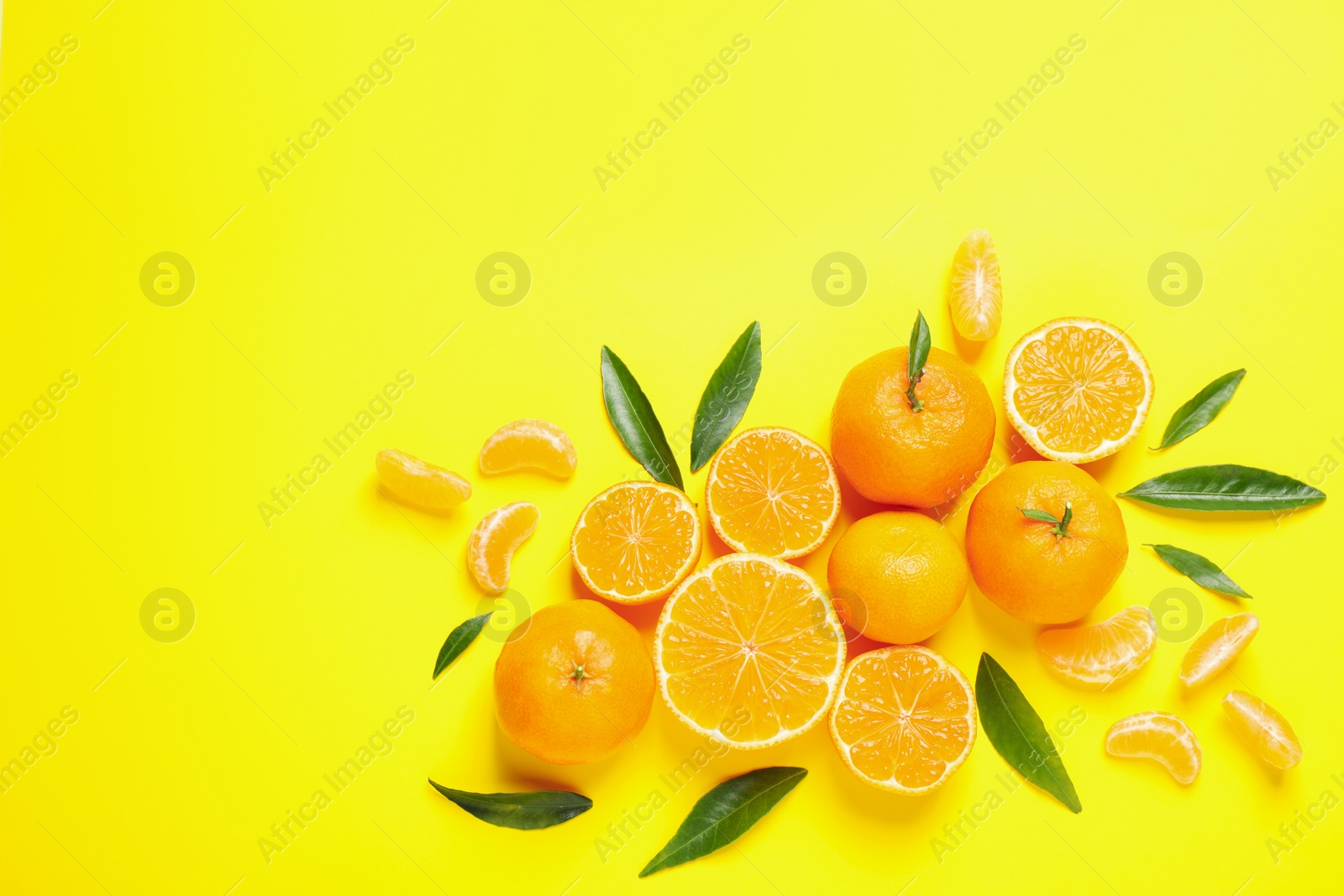 Photo of Flat lay composition with fresh ripe tangerines and leaves on yellow background. Citrus fruit