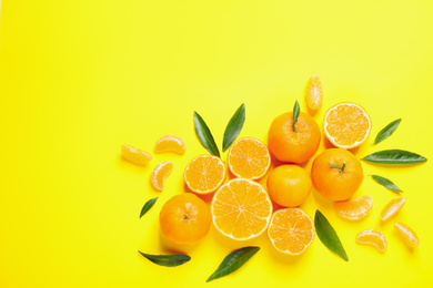 Flat lay composition with fresh ripe tangerines and leaves on yellow background. Citrus fruit