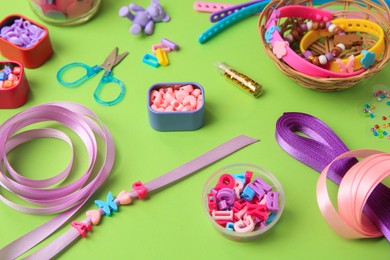 Photo of Handmade jewelry kit for children. Colorful beads, ribbons and supplies on green background
