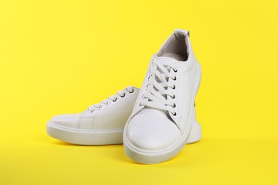 Photo of Pair of stylish white sneakers on yellow background