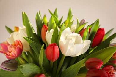 Photo of Beautiful bouquet of colorful tulips on beige background, closeup