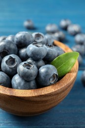 Photo of Bowl of fresh tasty blueberries on blue wooden table, closeup