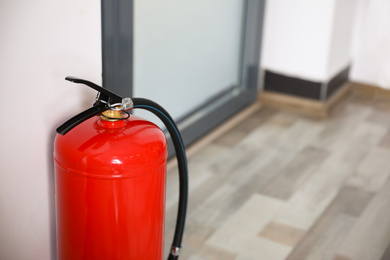 Fire extinguisher indoors, closeup. Space for text