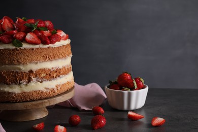 Tasty cake with fresh strawberries and mint on table against dark gray background