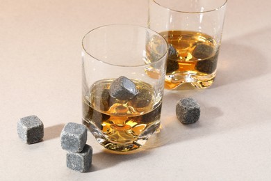 Photo of Whiskey stones and drink in glasses on light table, closeup