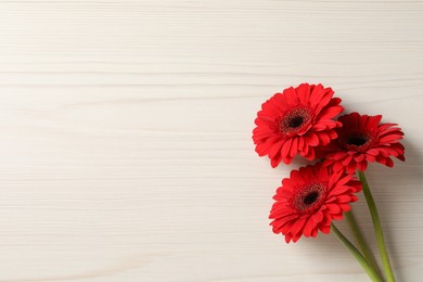 Photo of Bouquet of beautiful red gerbera flowers on wooden background, top view. Space for text