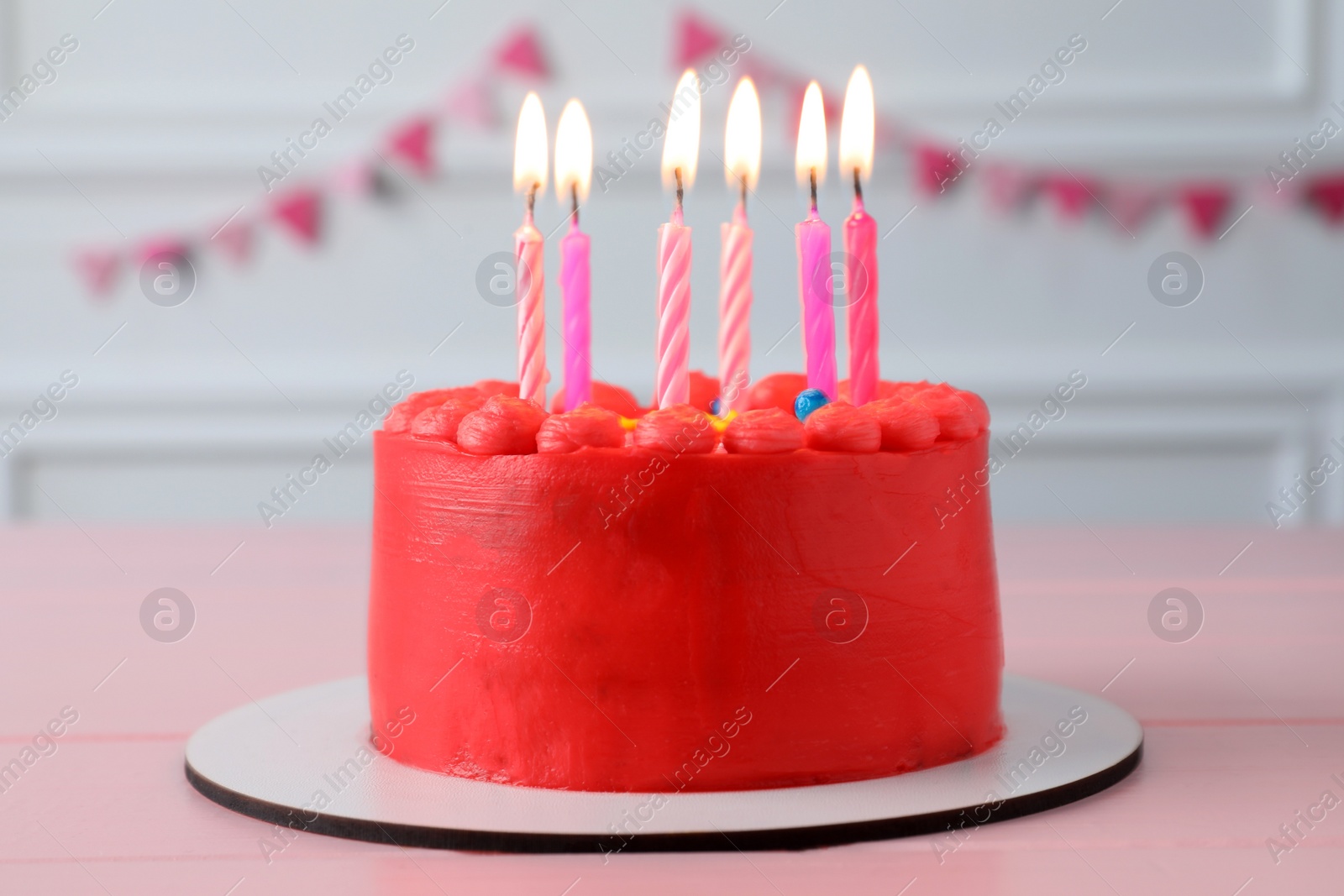 Photo of Cute bento cake with tasty cream and burning candles on pink wooden table