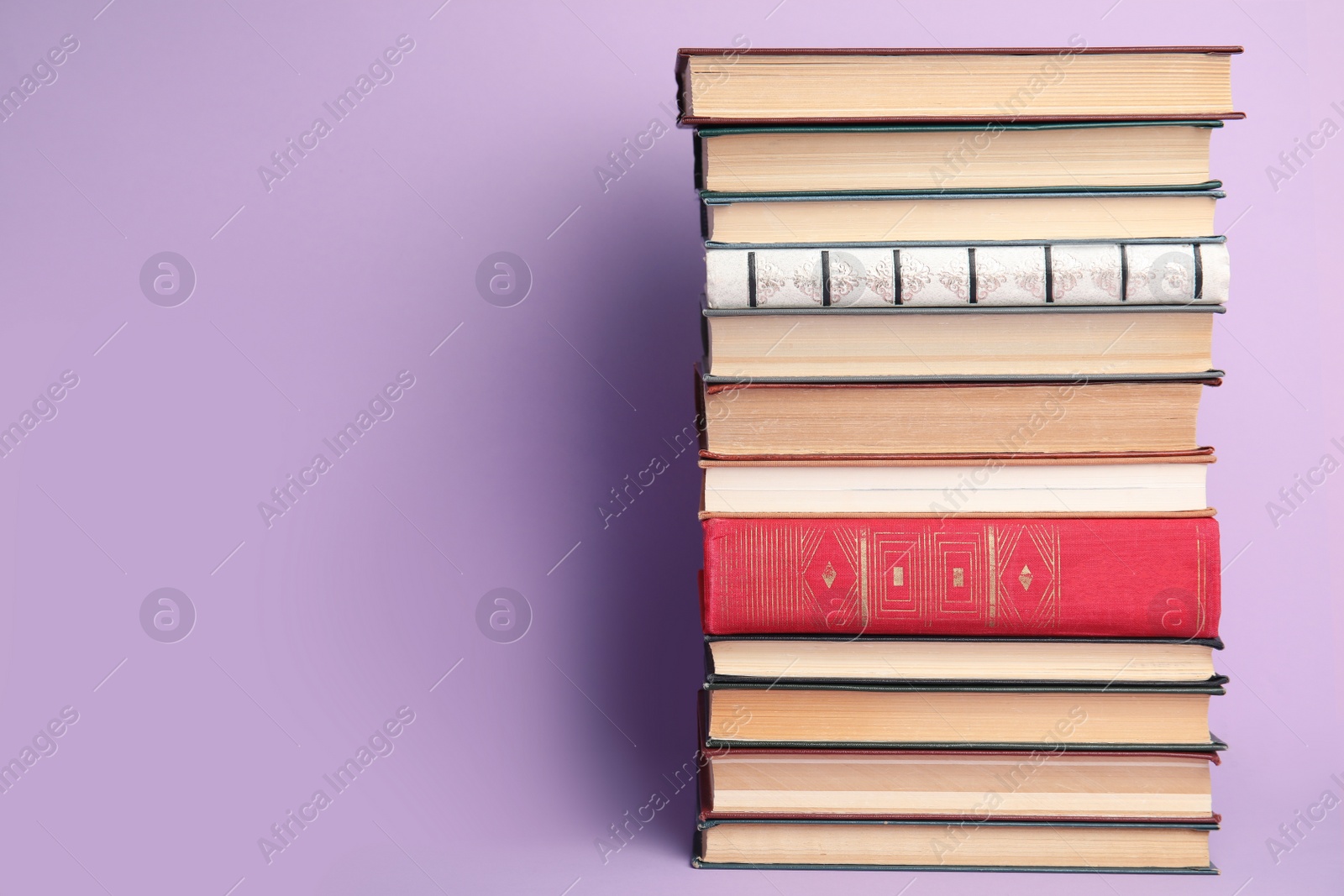 Photo of Stack of hardcover books on violet background. Space for text