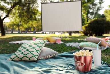 Photo of Popcorn and drink on blanket in open air cinema. Space for text