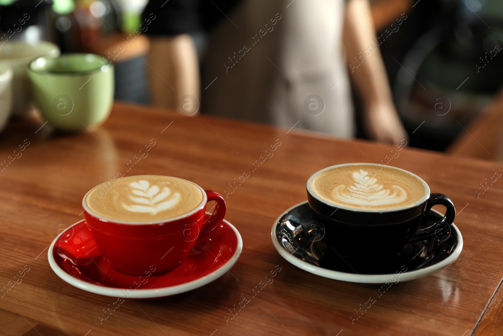 Photo of Cups of coffee on wooden counter in bar. Space for text